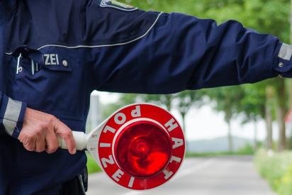Symbolbild HIV bei der Polizei: polizist winkt auto mit Stopschild aus dem verkehr