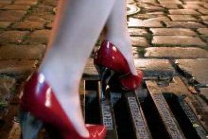 Stolperfalle: Füße in Stöckelschuhen gehen über Gulliabdeckung